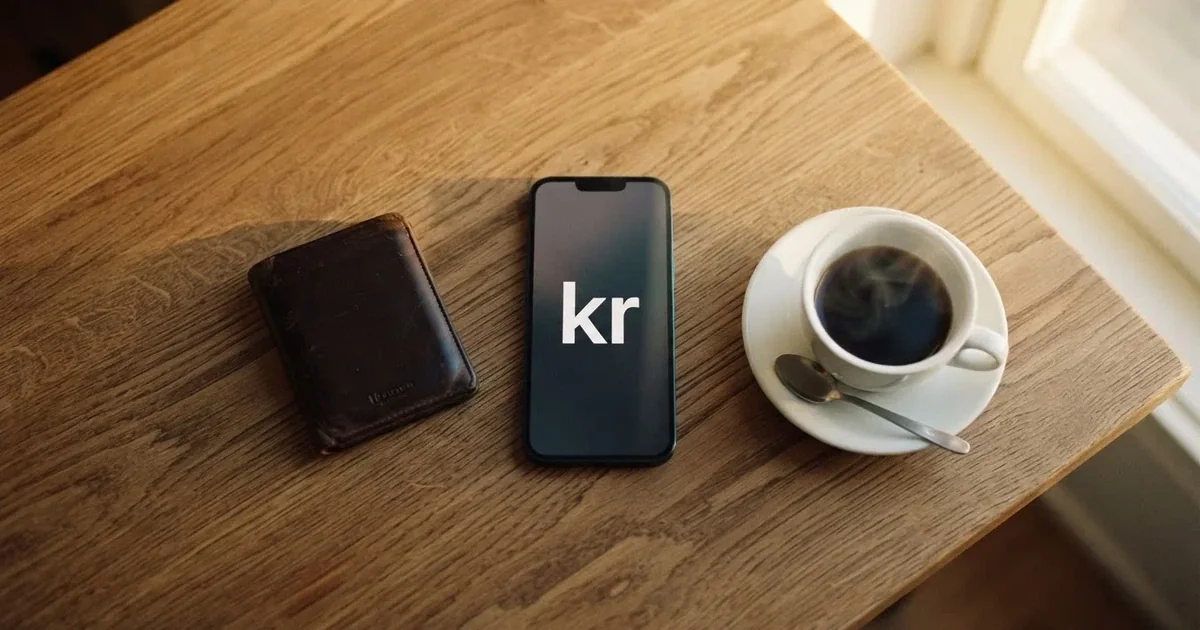 Mobiltelefon på ett träbord bredvid en plånbok och en kopp kaffe — 100 kr casino i sverige